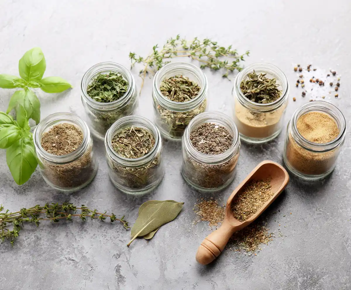 mediterranean pantry glass jars filled with dried herbs and spices on gray stone surface