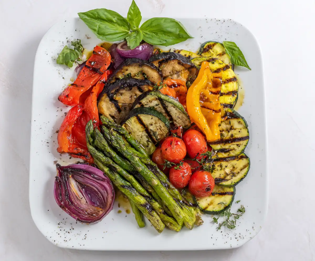 Mediterranean Roast vegetables Grilled with zucchini, eggplant, bell peppers, tomatoes, and asparagus on a white plate