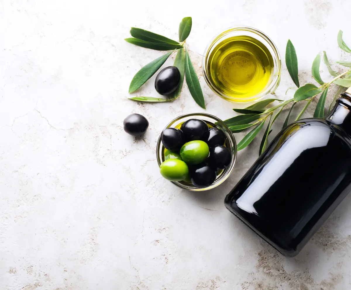 overhead view of types of olive oil in small bowls with green and black olives